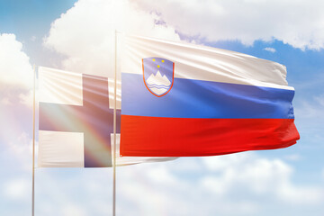 Sunny blue sky and flags of slovenia and finland