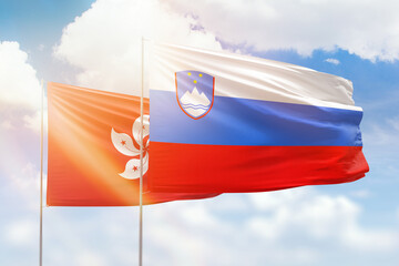 Sunny blue sky and flags of slovenia and hong kong