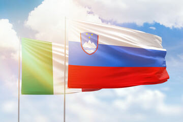 Sunny blue sky and flags of slovenia and italy