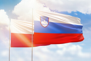 Sunny blue sky and flags of slovenia and poland