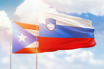 Sunny blue sky and flags of slovenia and puerto rico