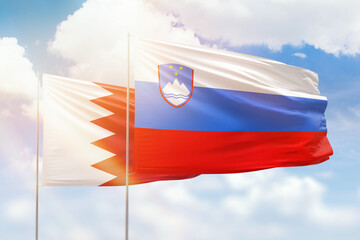 Sunny blue sky and flags of slovenia and bahrain