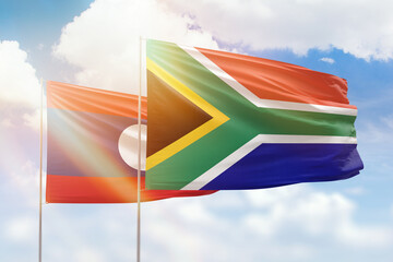 Sunny blue sky and flags of south africa and laos