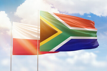 Sunny blue sky and flags of south africa and poland