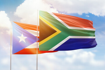 Sunny blue sky and flags of south africa and puerto rico