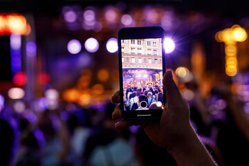 People holding their smartphones at concert and taking pictures.