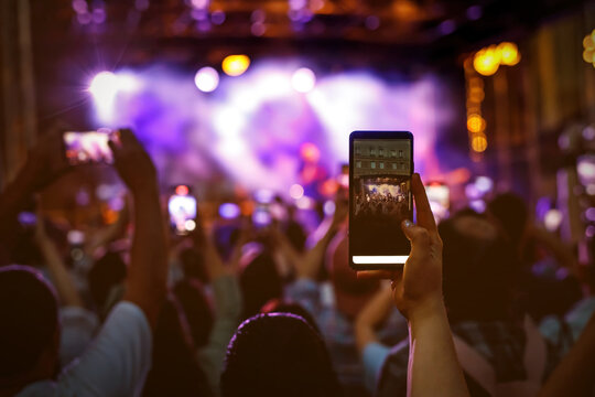 People holding their smartphones at concert and taking pictures.