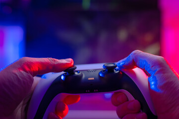 Gamepad in the hands of a gamer. Close-up. Neon lighting. Video games, online games with friends,...