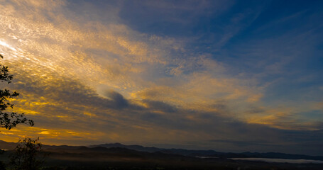 Obraz premium Blue golden sky sunrise dramatic beautiful landscape mountain. Dawn sky gold dusk time cloudscape with sunlight. Dramatic sunset over mountain landscape. Beautiful landscape foggy hills twilight time