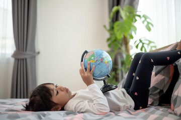 Beautiful girl looking at an earth globe and learning about geography.