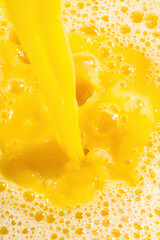 Naklejka na ściany i meble Closeup of splashing orange juice, top view. Splash of fresh sweet orange, mango, fruit juice. Freeze motion of pouring orange juice .