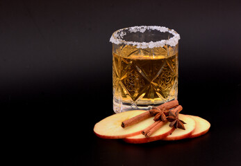 A crystal glass of cider with sugar around the rim, red apple slices, star anise and cinnamon...