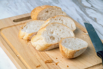 Fresh sliced baguette bread on wooden table. Healthy eating breakfast.	