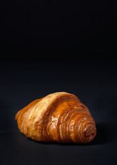 Fresh croissants bread and a cup of coffee on black background. French breakfast.