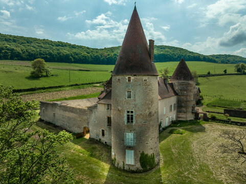 Aerial view of Chateau de Nobles near Brancion France with restored circular towers, renaissance palace building on the rolling hills
