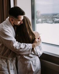 Happy couple in the hotel on window kiss and hug each other