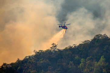 Fototapeta na wymiar Fire fighting helicopter dropping water onto wildfire