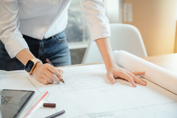 Selective focus, Asian female architect or engineer Drawing the design of the building structure in the blueprint. Asian female architect or engineer Sit and analyze, design projects in the office.