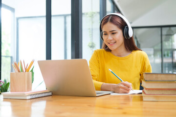 Young collage student using computer and mobile device studying online.