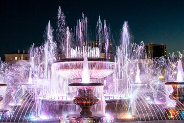 Gorgeous splashes of illuminated musical fountain against the night sky