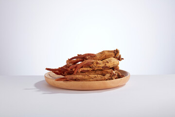 A front view of ginseng decorated in wooden dish in white background 