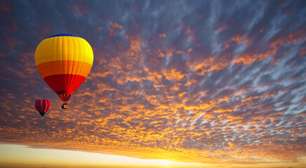 Hot air balloon floating in orange clouds like a sea of fire in the morning before sunrise. Balloons for sports and relaxation, recreation.