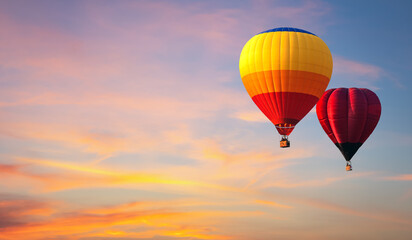 Hot air balloon floating in vivid sky with cloud painted by the sun before sunset in winter. Colorful sky on evening time. Bright blue, orange and yellow colors sunset .