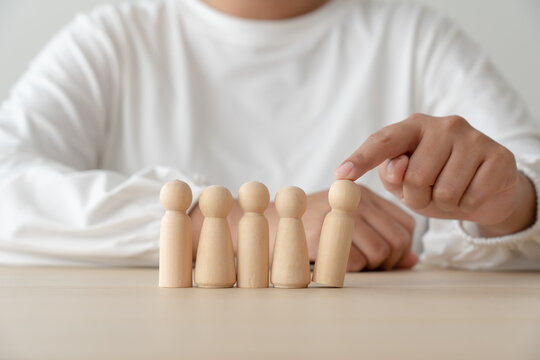 Woman and wooden human figures concept of recuitment, leadership, teamwork. Winner was pick up and loser was ignore.