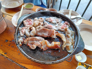 Grilled bacon on a hot pan, on a wooden table