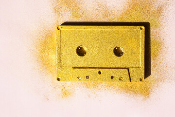 Retro audio cassette on pink. Old golden colour cassette tape.