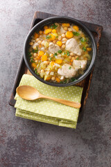 Minestra dei morti or Soup of the Dead, is a hearty, simple soup made with pork and chickpeas closeup in the plate on the wooden board. Vertical top view from above