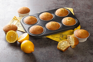 Golden muffins with poppy seeds and lemon zest close-up in a metal muffin pan on the table. horizontal
