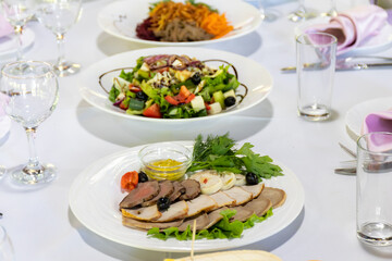 A plate with cold cuts and salads on a table served for a banquet
