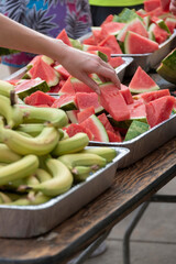 Hand taking watermelon piece from stack.