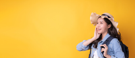 Happy smiling Asian girl traveling backpacking. tourists carrying a backpack on a yellow background. vacation travel, tour, relax, journey in the world