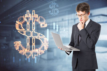 businessman with laptop thinking while standing on abstract blurry office interior background with glowing dollar sign hologram. Online banking, technology, data and finance concept. Double exposure.