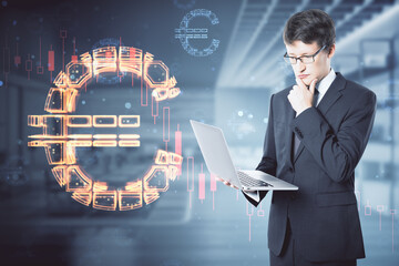 businessman with laptop thinking while standing on abstract blurry office interior background with glowing euro sign hologram. Online banking, technology, data and finance concept. Double exposure.