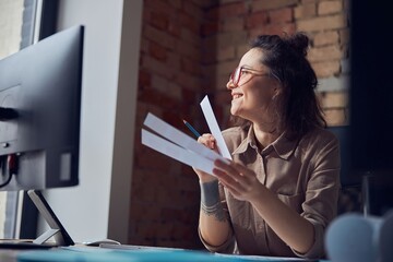 Smiling female interior architect or designer looking at the window, holding color samples while...