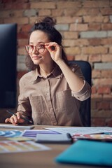 Concentrated female interior architect or designer working on a project, using computer, selecting...