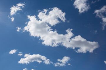 long white cloud surrounded by small clouds, in the blue sky
