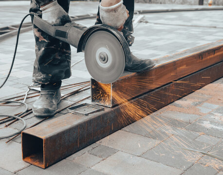 A worker cuts metal at a construction site.