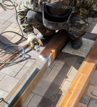 A worker works with metal welding at a construction site.