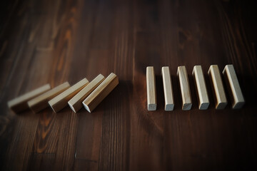 domino effect concept with wooden tiles blocked by hourglass with background