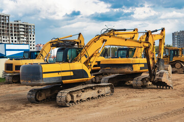 Powerful excavators at a construction site against a cloudy evening sky. earthmoving construction equipment. Lots of excavators.