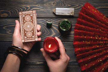 Tarot cards in fortune teller hands on the old wooden table flat lay background concept.