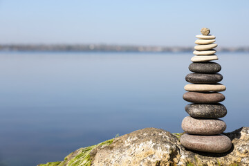 Stack of stones on rock near river, space for text. Harmony and balance concept