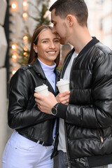 Lovely young couple with cups of coffee enjoying time together outdoors, closeup. Romantic date