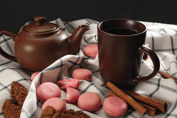 Teapot and cup on kitchen cloth with scattered pink macarons