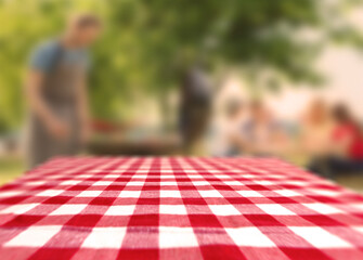 Table with checkered picnic cloth outdoors on sunny day. Space for design