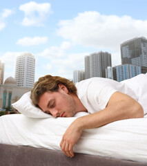 Man sleeping in bed and beautiful view of cityscape on background. Good sleep despite of urban...